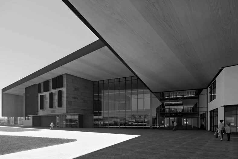 Modern glass-fronted building with a large overhanging roof and people walking outside, in black and whiteseems dramatic.